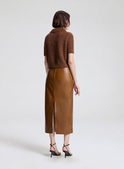 Woman wearing a brown knit top and leather skirt on a white background