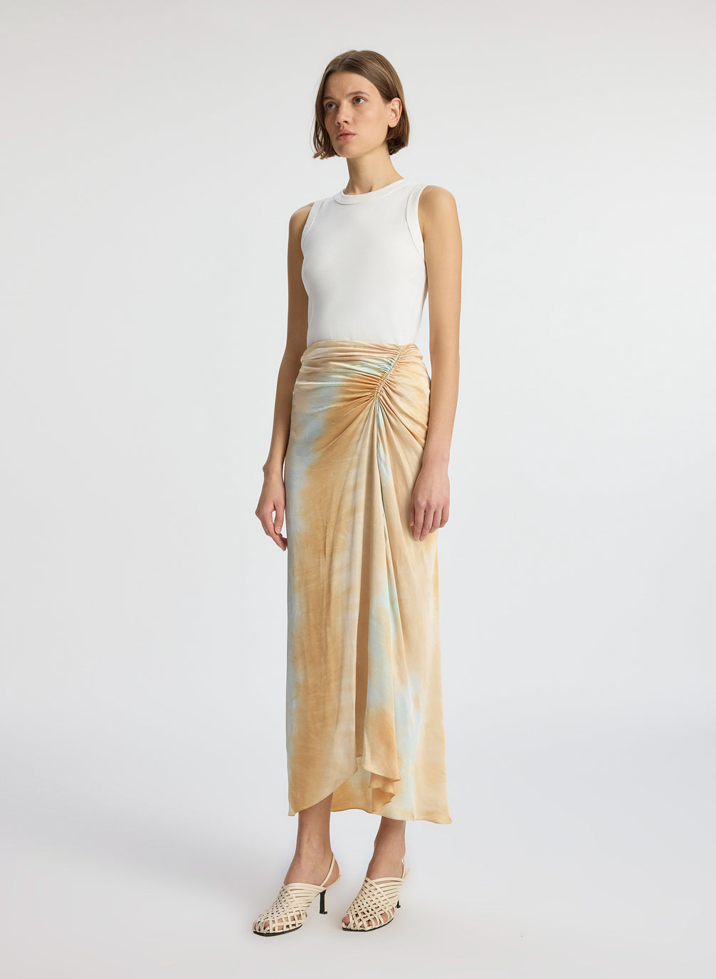 side view of woman wearing white tank top and blue and beige midi skirt