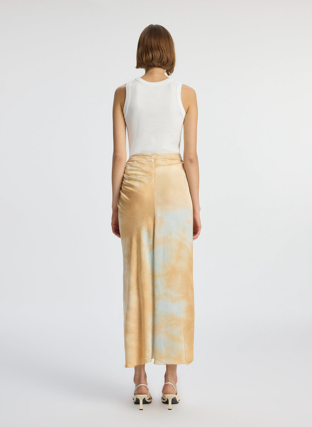 back view of woman wearing white tank top and blue and beige midi skirt