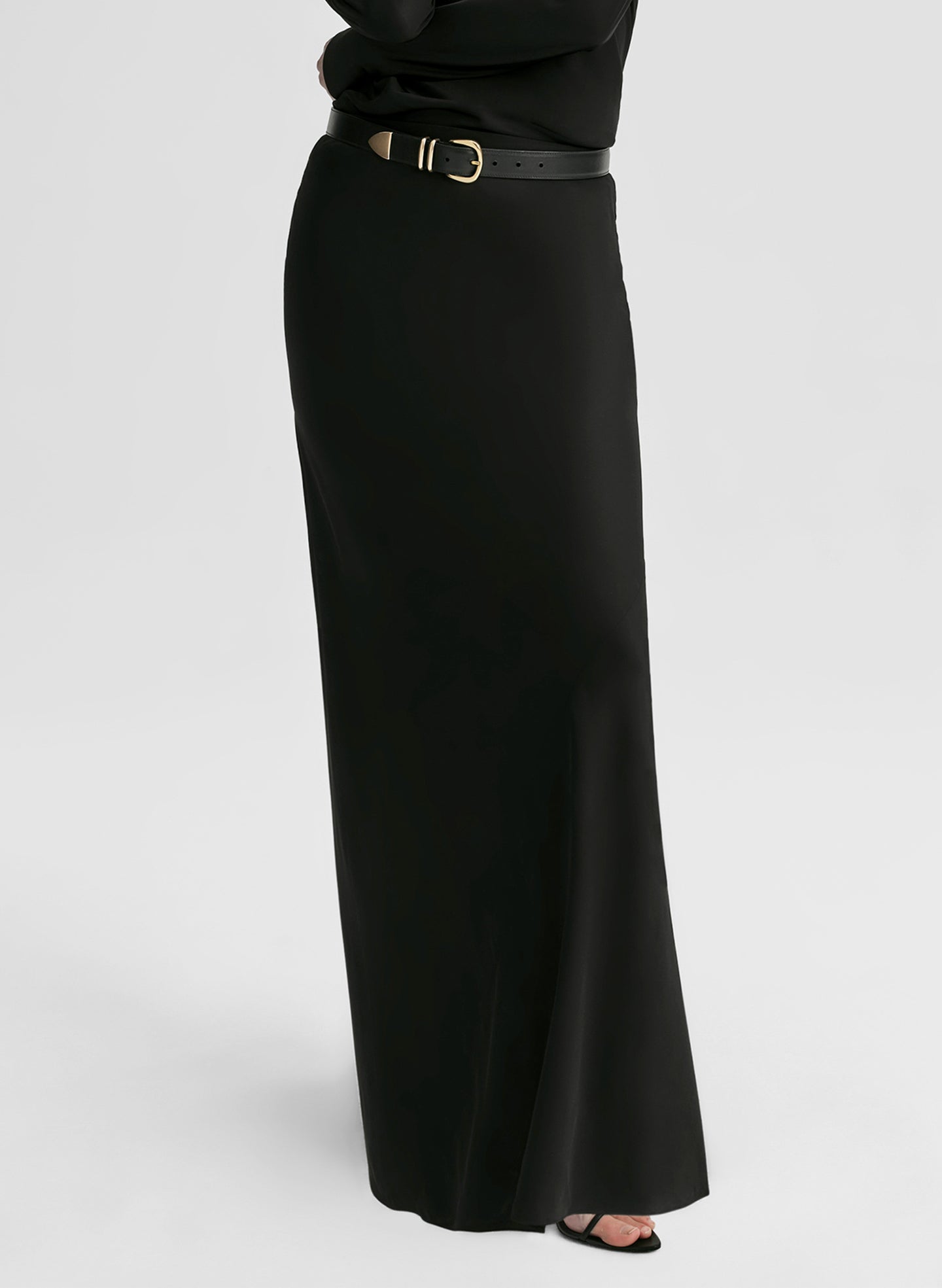 Woman wearing a black long-sleeve top and black skirt on a white background