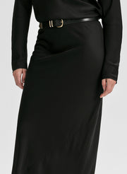 Woman wearing a black long-sleeve top and black skirt on a white background