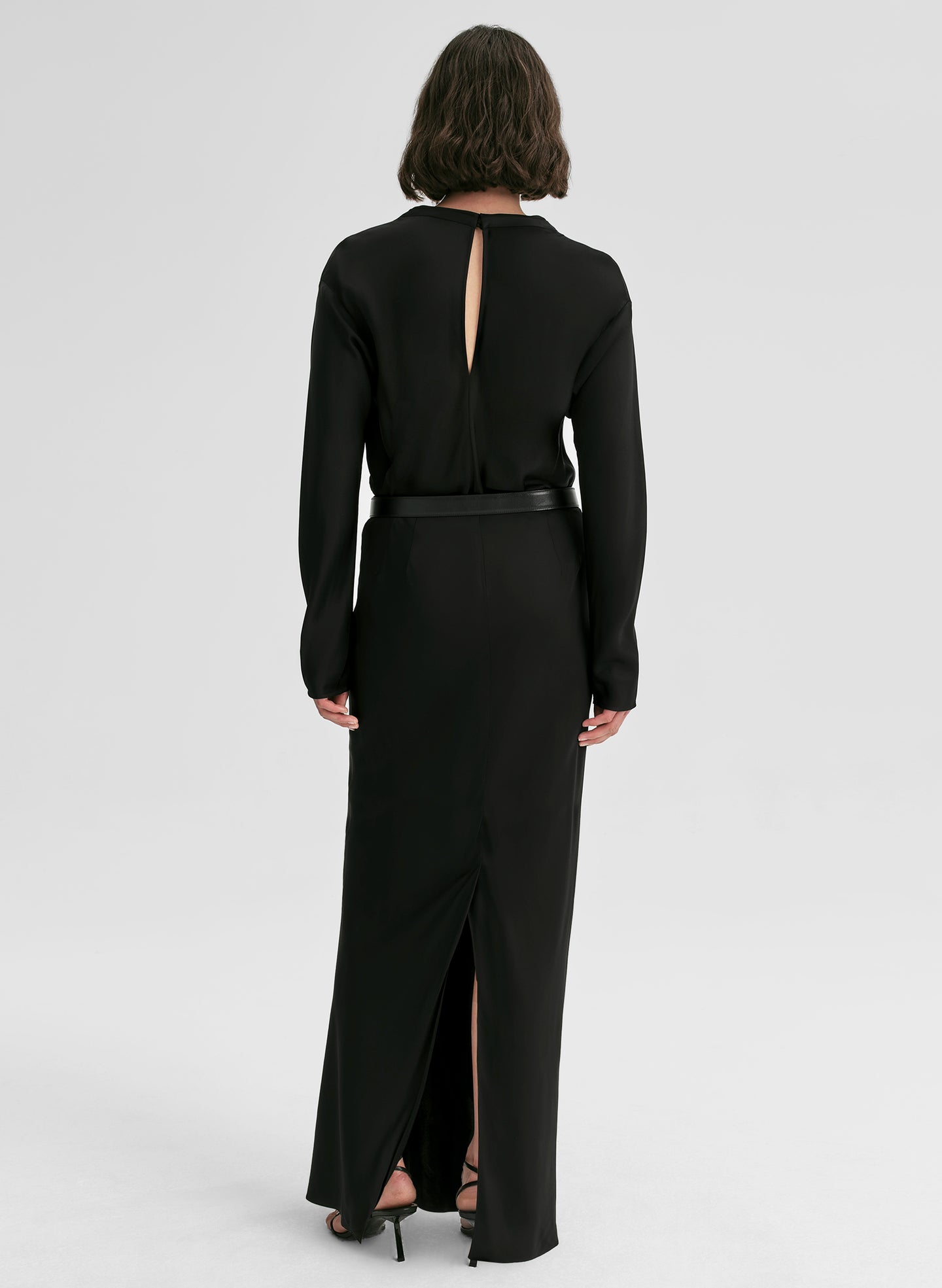 Woman wearing a black long-sleeve top and black skirt on a white background