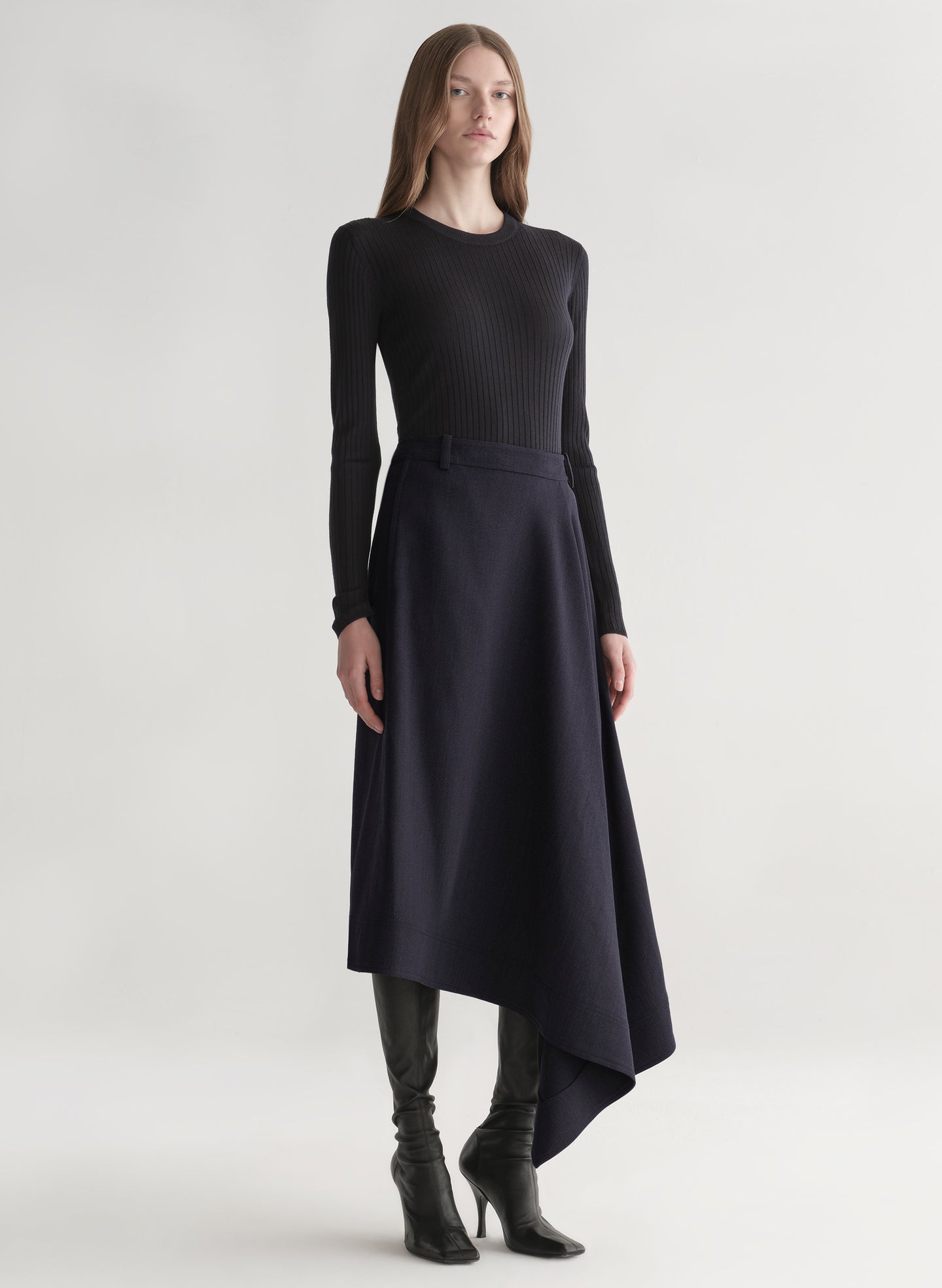 Woman wearing a black top and navy skirt on a white background