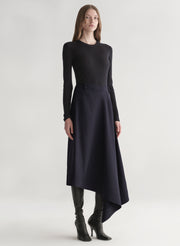 Woman wearing a black top and navy skirt on a white background