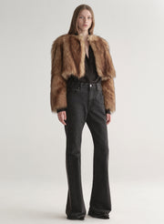 Woman wearing a brown faux fur coat over a black outfit on a plain background