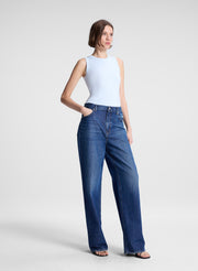 woman wearing light blue tank top and dark blue denim wide leg jeans