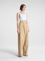 woman wearing light blue cropped tank top and beige draped pants