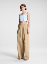 woman wearing light blue cropped tank top and beige draped pants