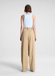 woman wearing light blue cropped tank top and beige draped pants