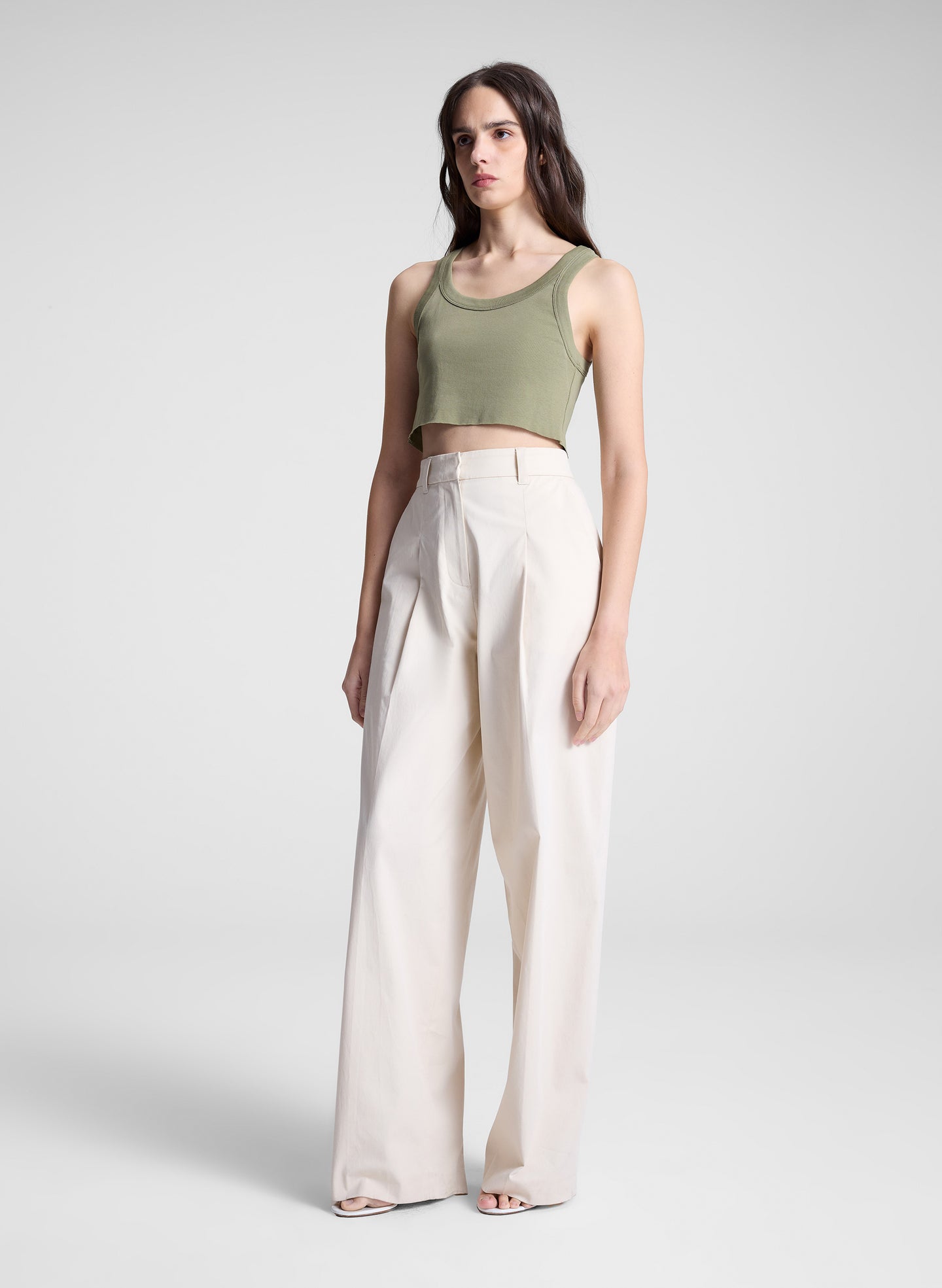 woman wearing green cropped tank and white pants