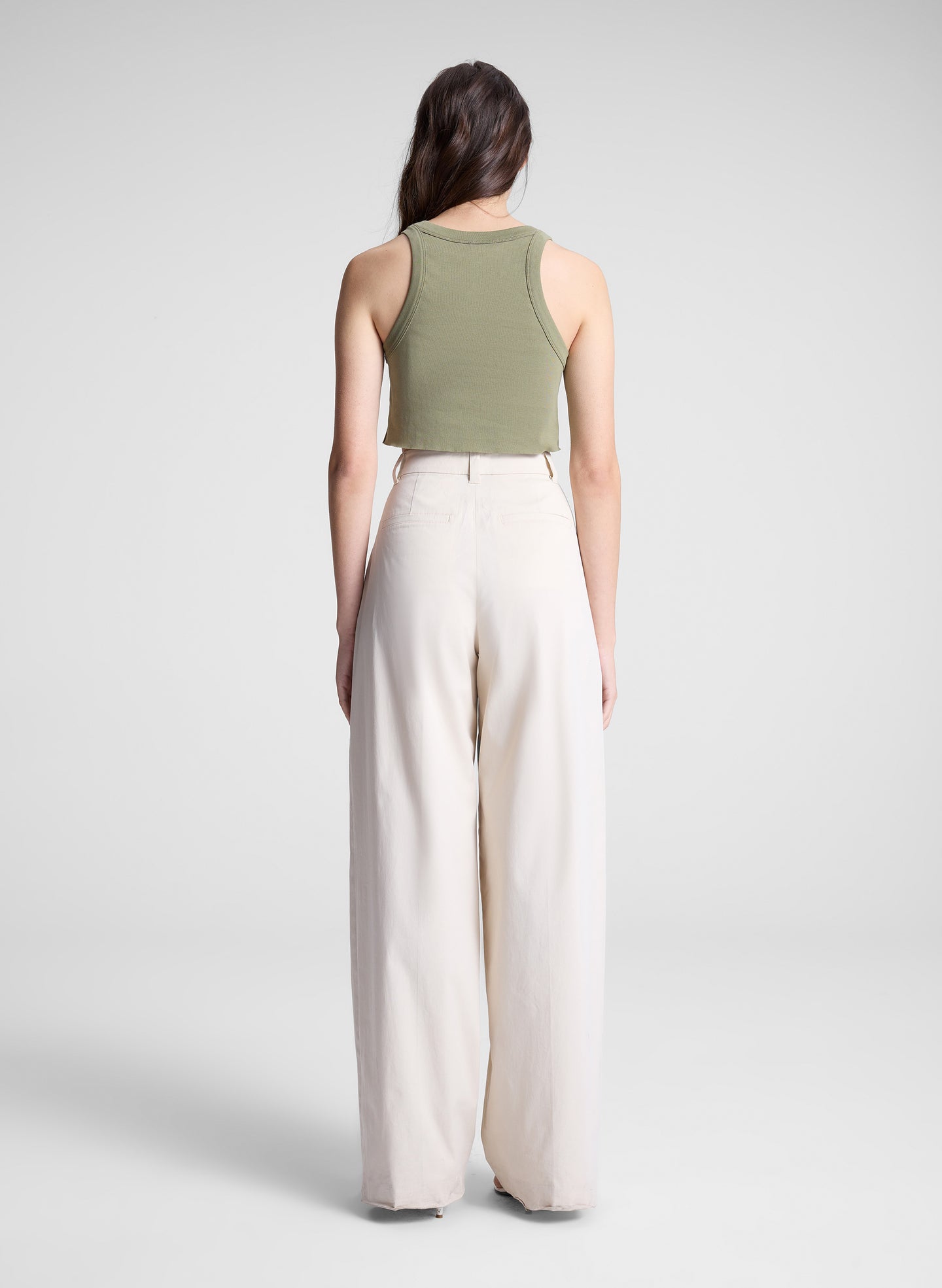 woman wearing green cropped tank and white pants