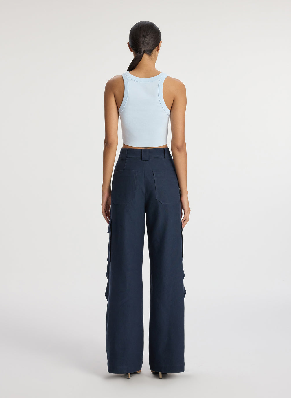 back view of woman wearing light blue cropped rib tank top and navy blue cargo pants