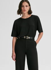 Woman wearing a black outfit with a belt on a white background