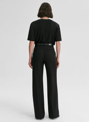 Person wearing a black outfit with wide-leg pants on a white background