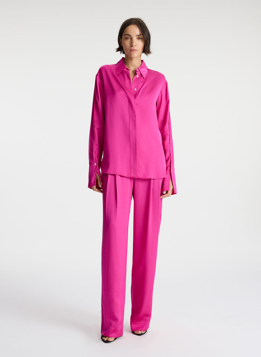 front view of woman wearing bright pink scalloped detailed long sleeve satin shirt and bright pink pants