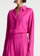 detail view of woman wearing bright pink scalloped detailed long sleeve satin shirt and bright pink pants