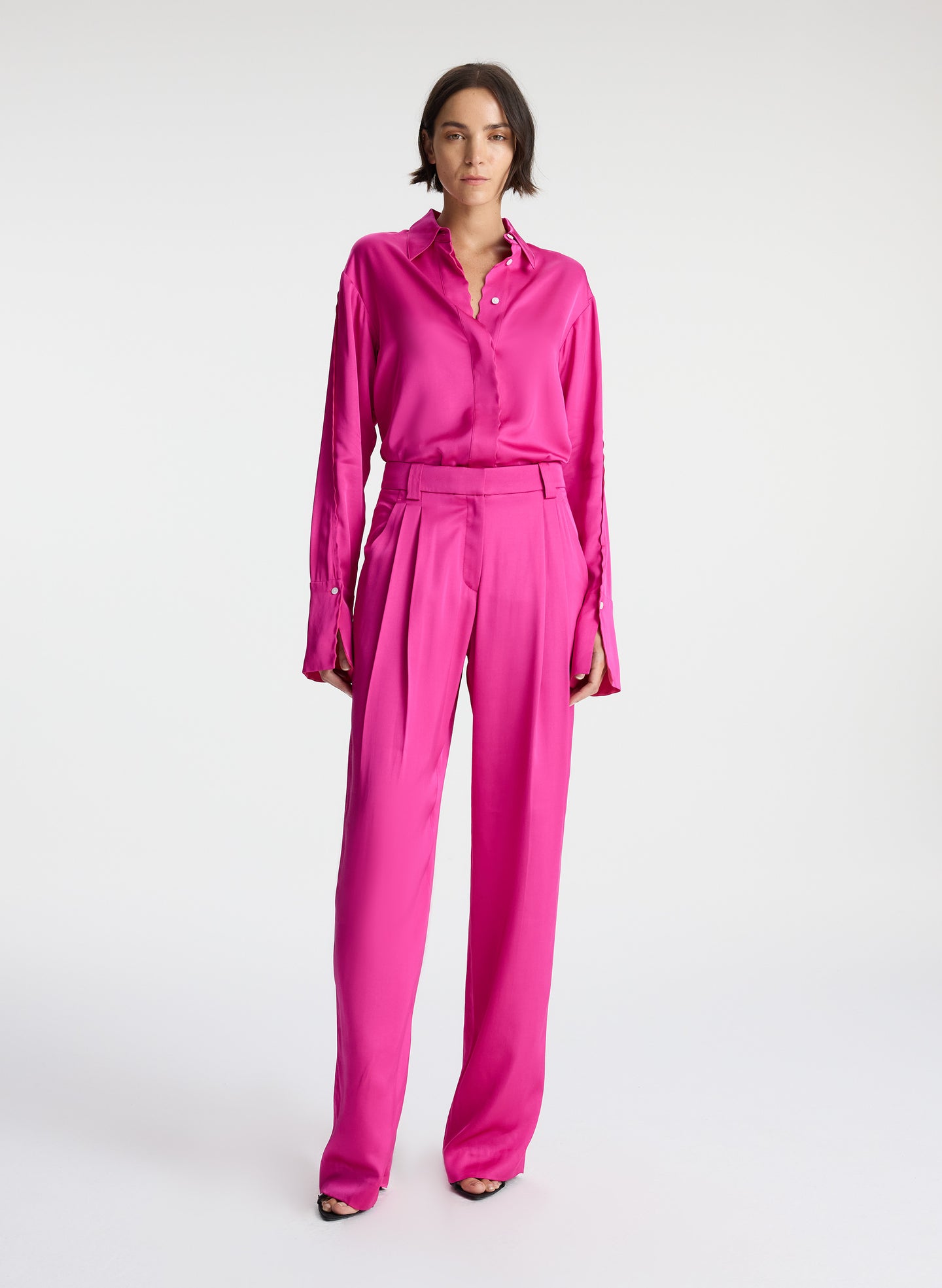 front view of woman wearing pink button down collared satin long sleeve shirt with matching pink satin pants