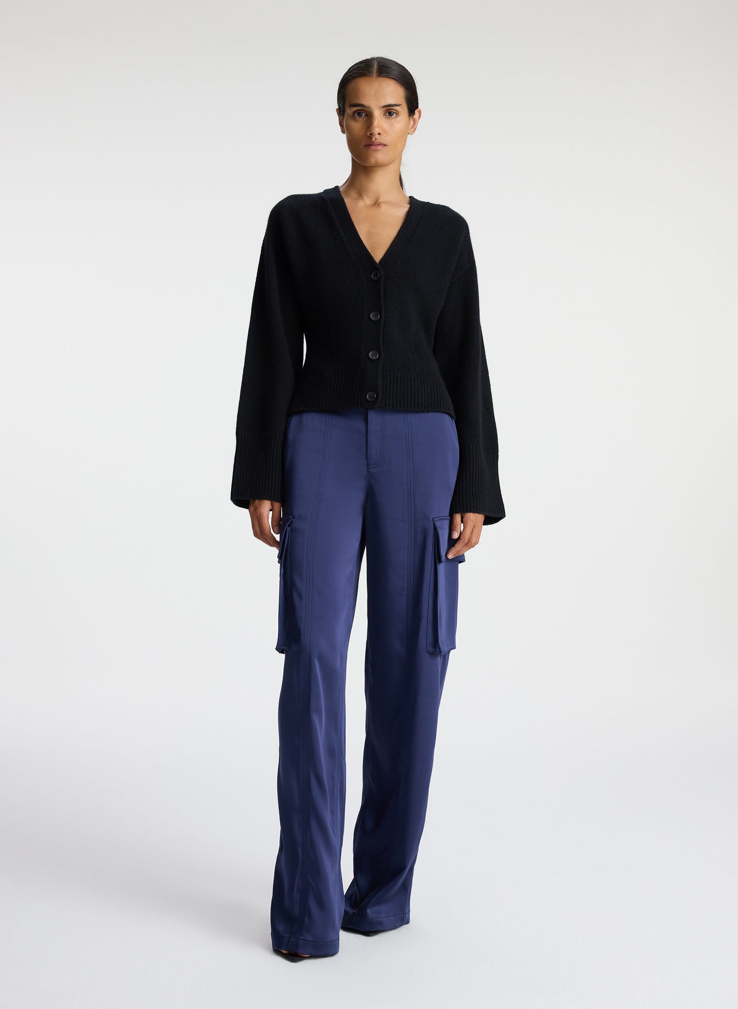 front view of woman wearing black cardigan with navy blue cargo pants