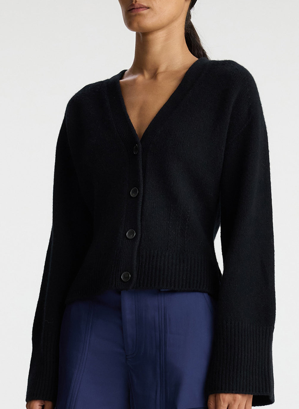 side view of woman wearing black cardigan with navy blue cargo pants