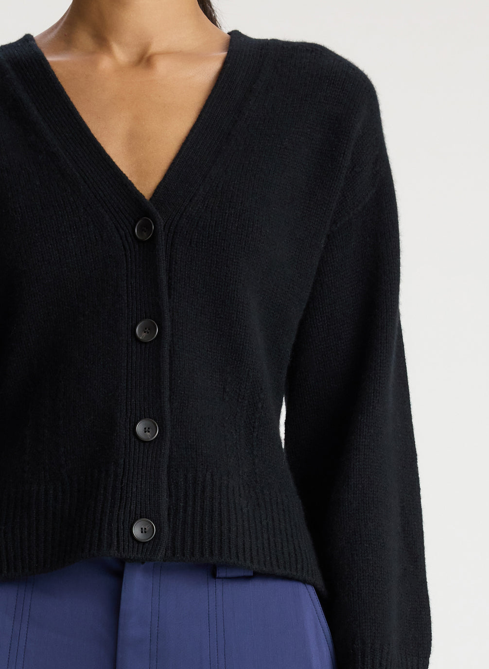 detail view of woman wearing black cardigan with navy blue cargo pants