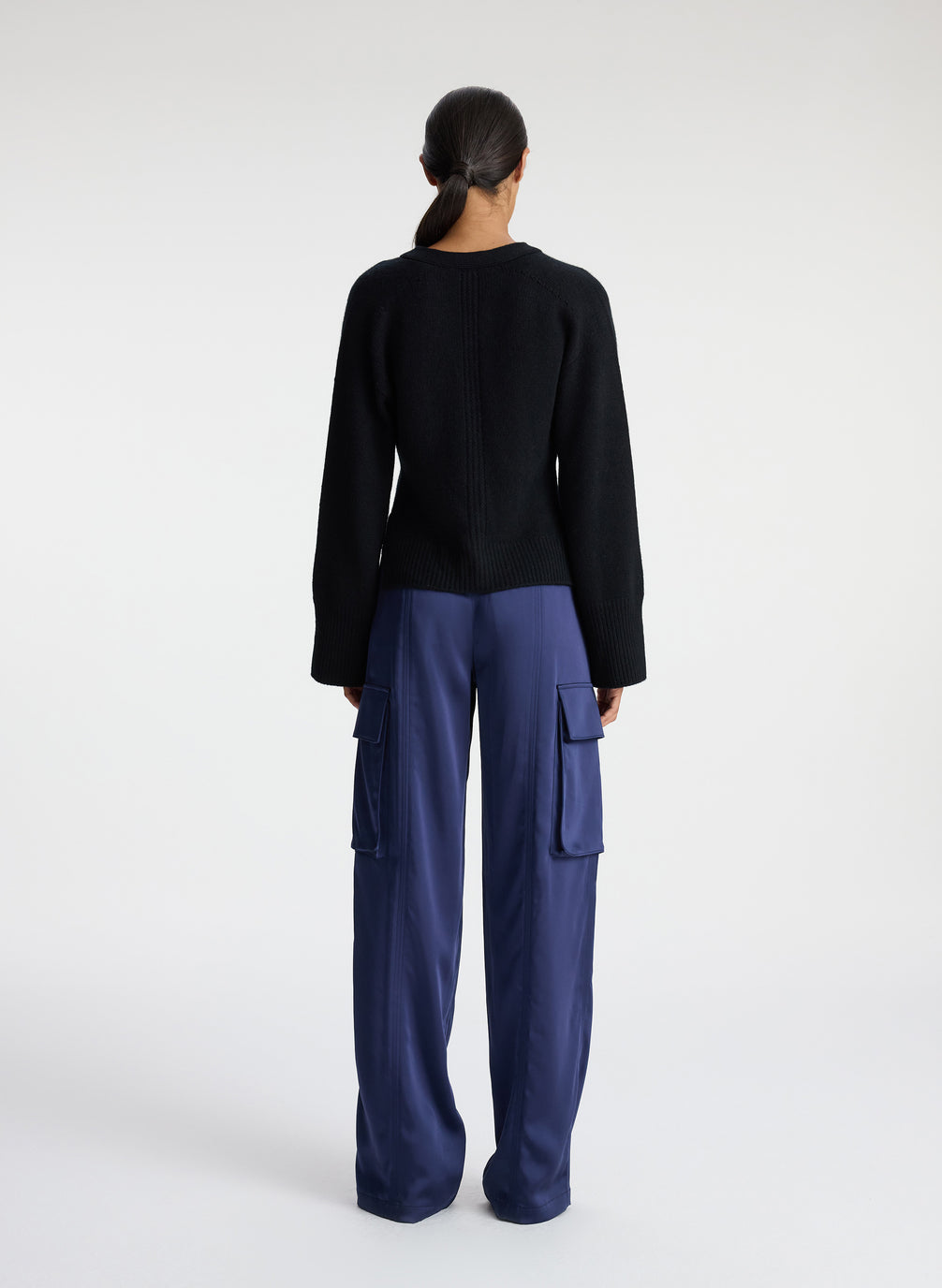back view of woman wearing black cardigan with navy blue cargo pants