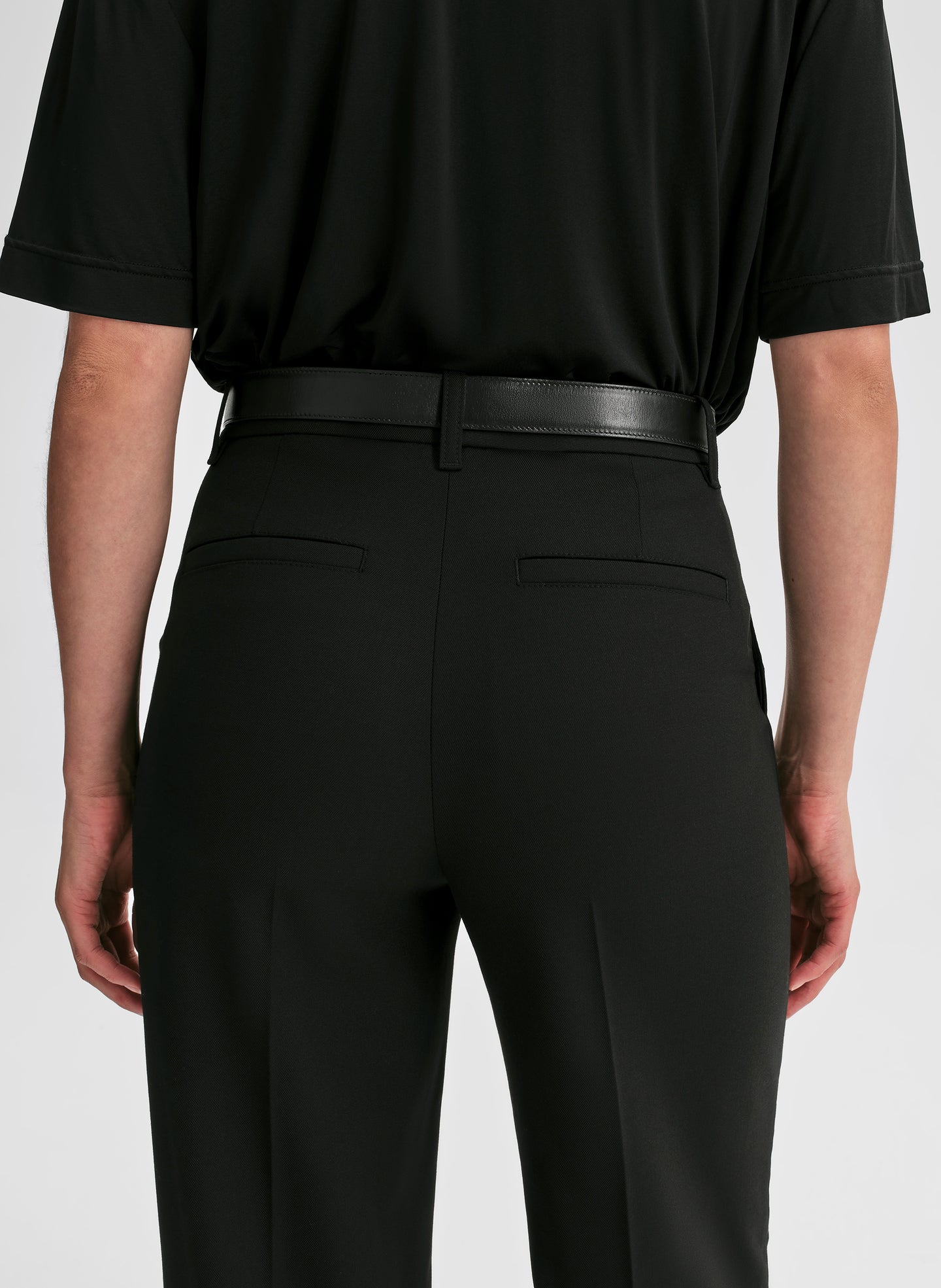 Person wearing a black shirt and black pants on a white background