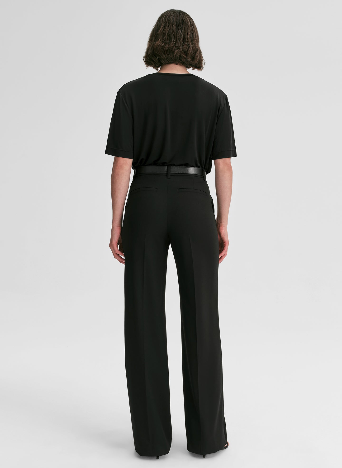 Person wearing a black outfit with wide-leg pants on a white background