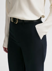 Woman wearing a white blouse and dark blue high-waisted pants on a white background