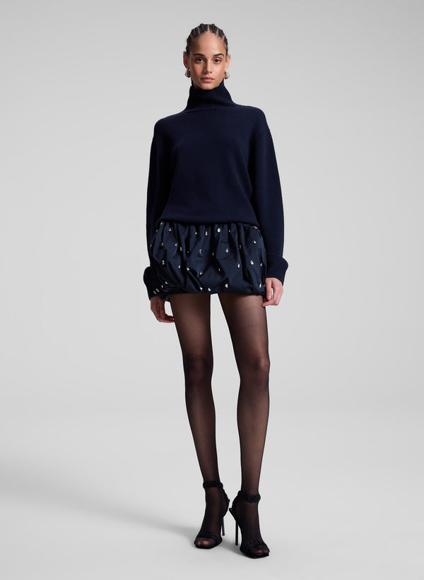 woman wearing navy sweater and navy blue embellished bubble mini skirt