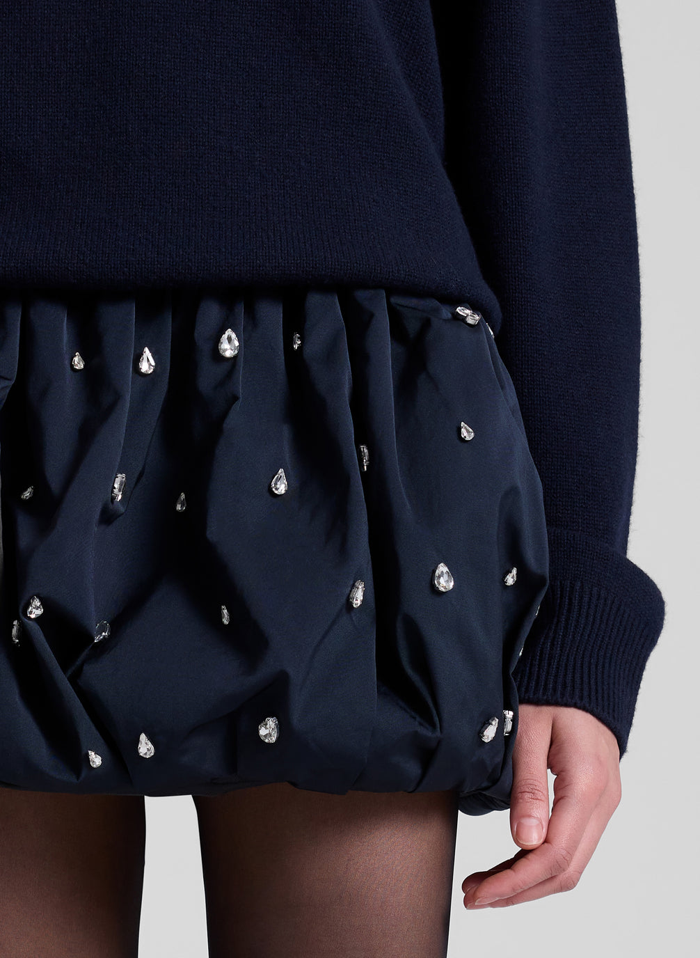 woman wearing navy sweater and navy blue embellished bubble mini skirt