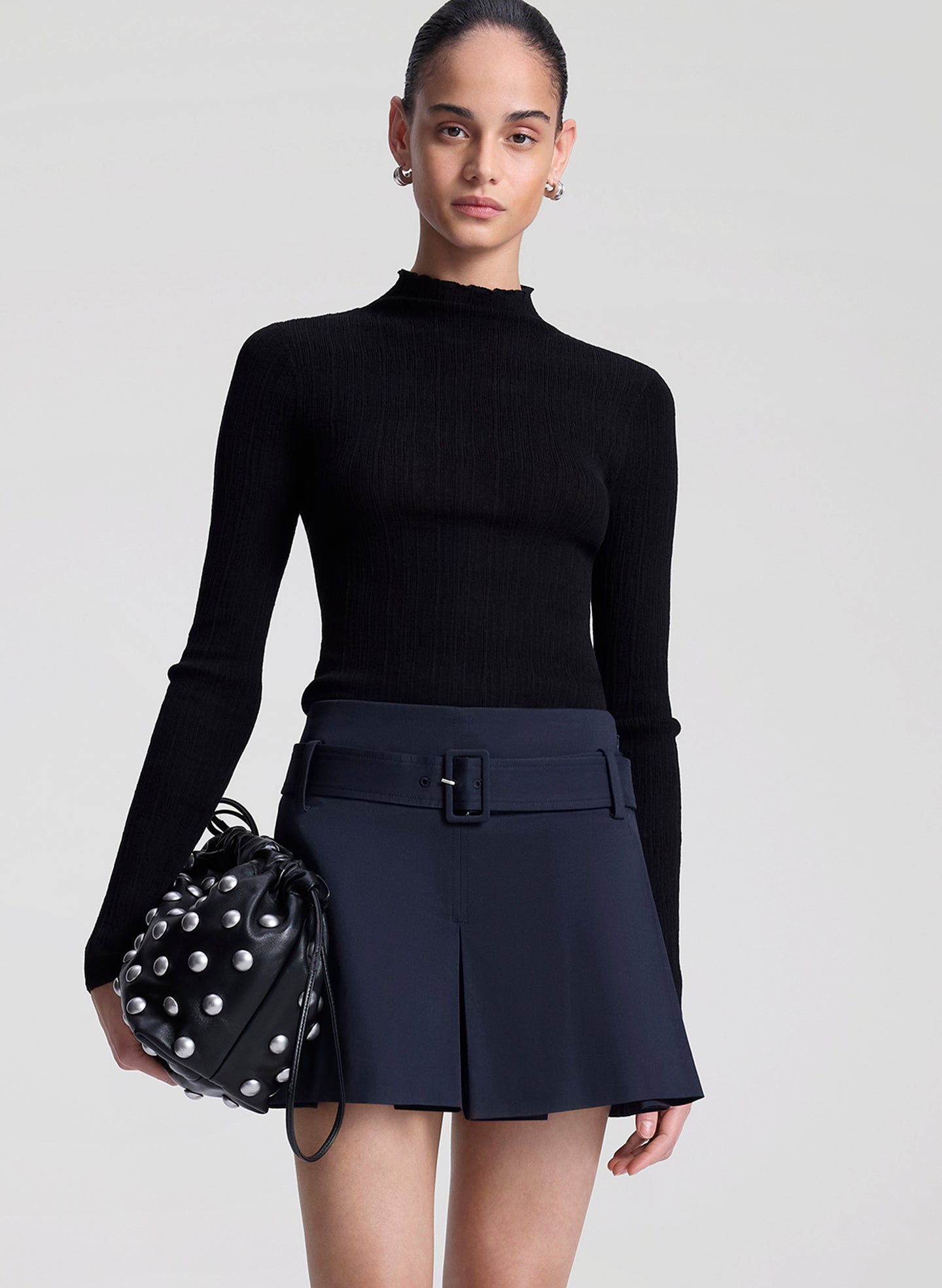 woman wearing black fine gauge voile knit top and navy blue skort