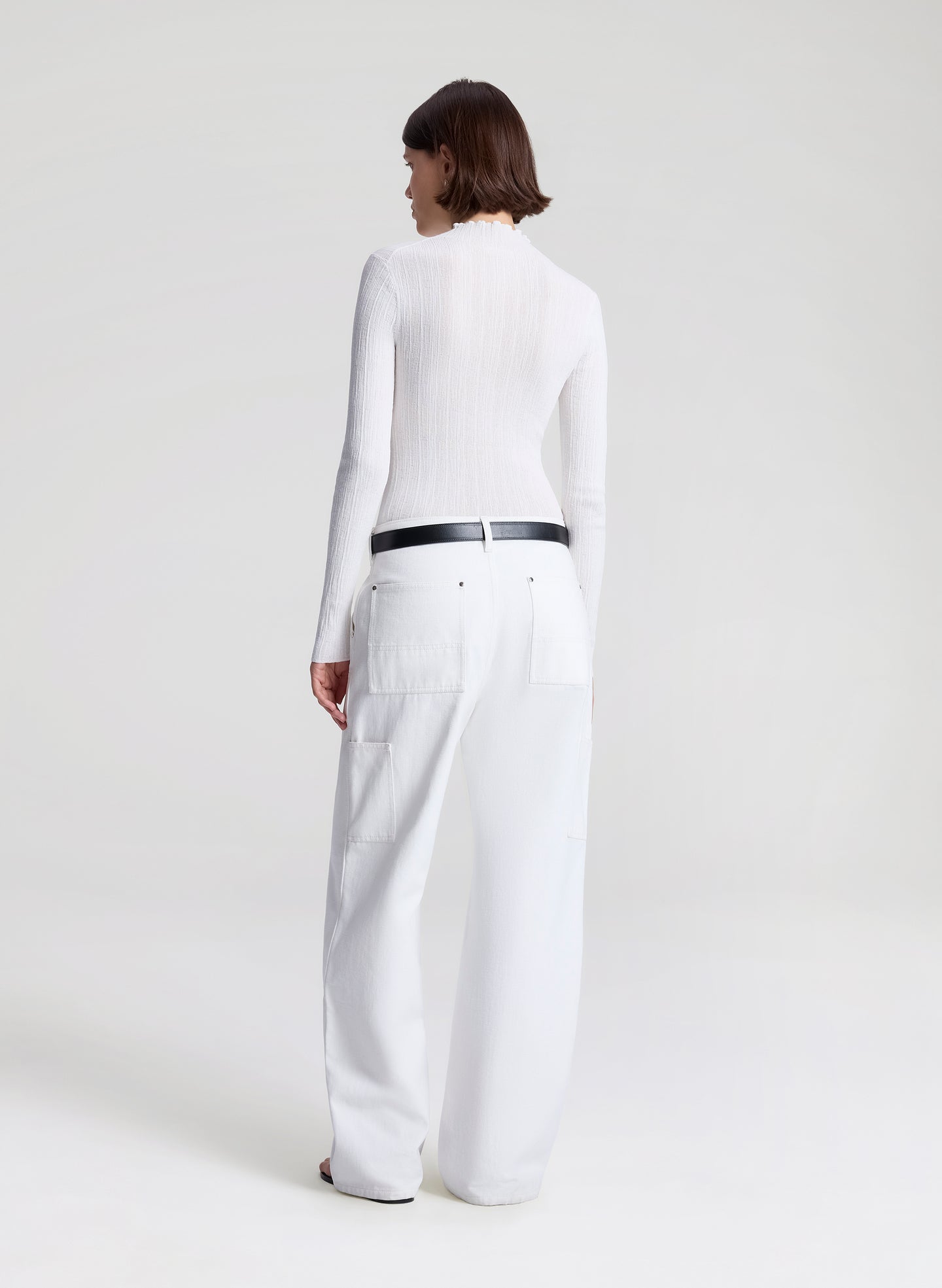 woman wearing white fine gauge voile knit top and white denim jeans