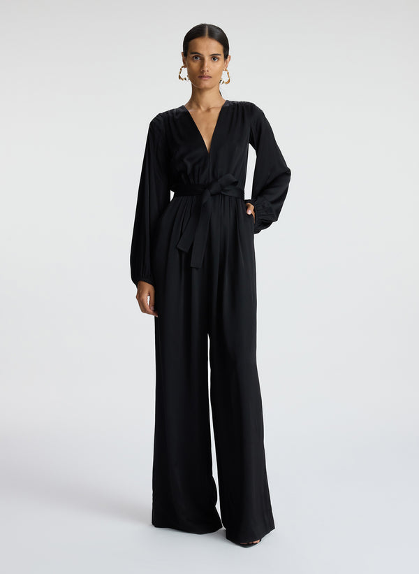 front view of woman wearing black satin long sleeve jumpsuit