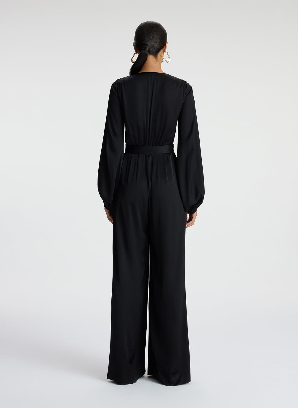 back view of woman wearing black satin long sleeve jumpsuit