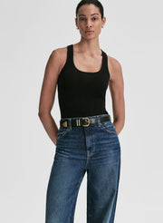Woman wearing a black tank top and blue jeans on a plain background