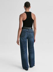 Person wearing blue jeans and a black tank top on a white background