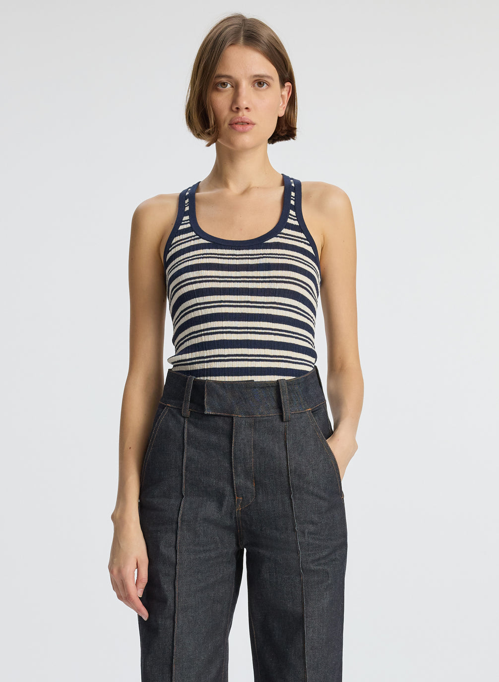front view of woman wearing navy blue striped tank top and dark wash raw denim jeans