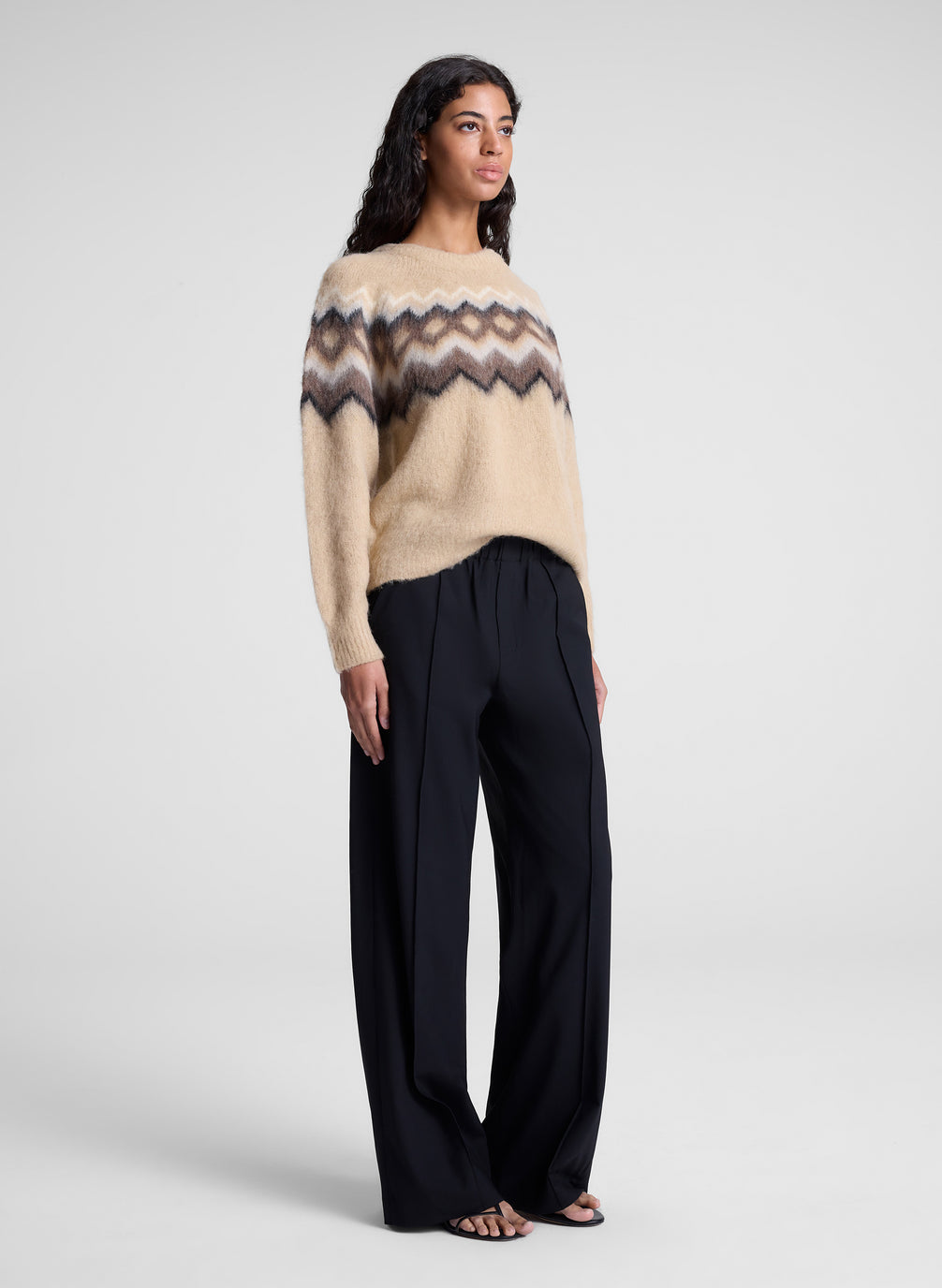 woman wearing tan fairisle sweater and black pants