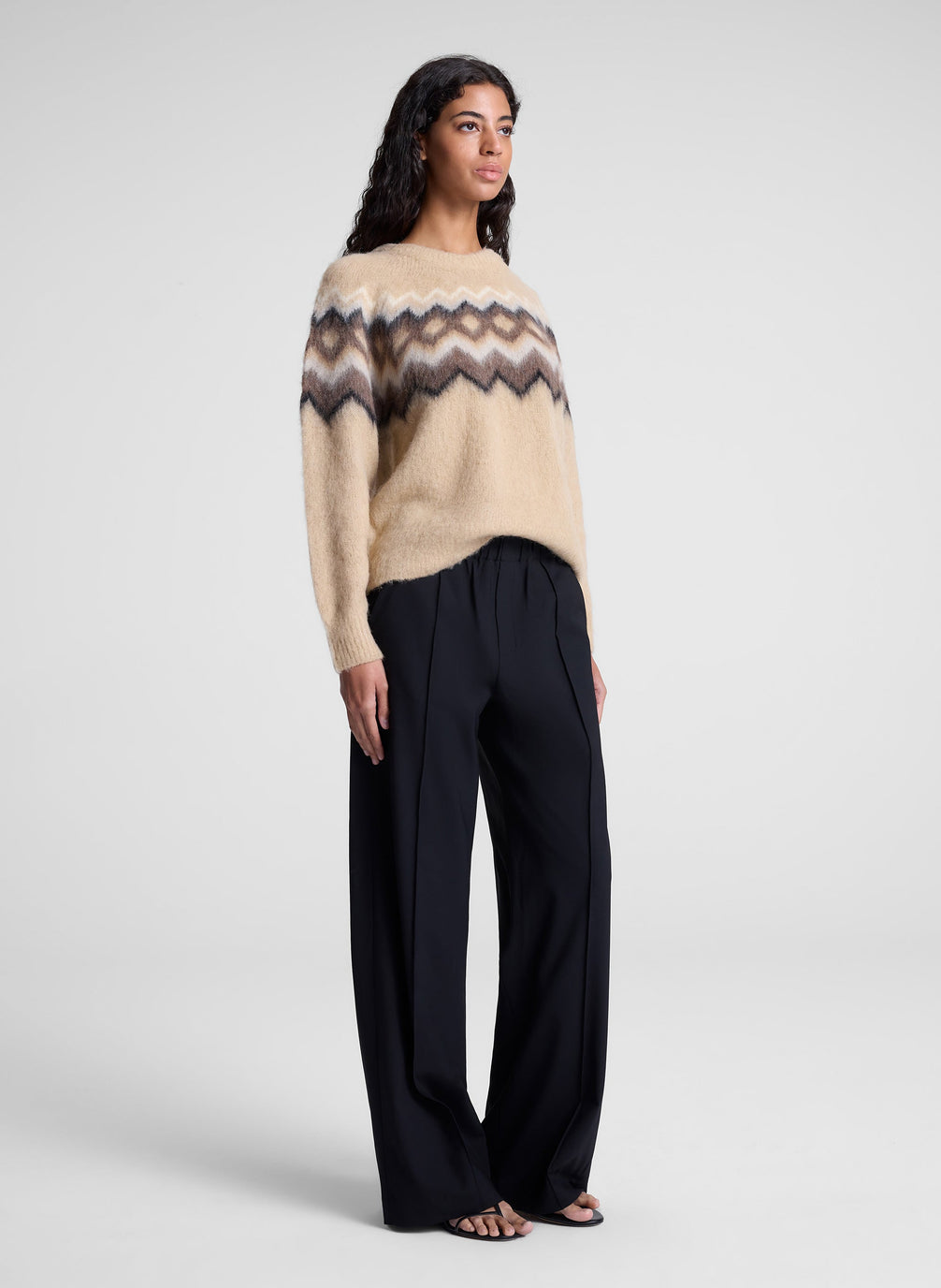 woman wearing tan fairisle sweater and black pants