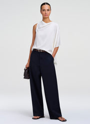 woman wearing white draped top and blue pants