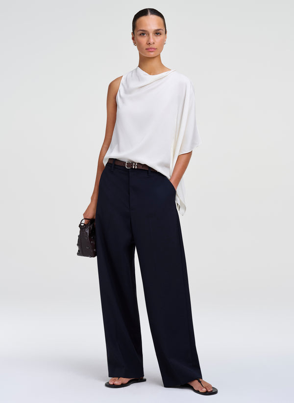 woman wearing white draped top and blue pants
