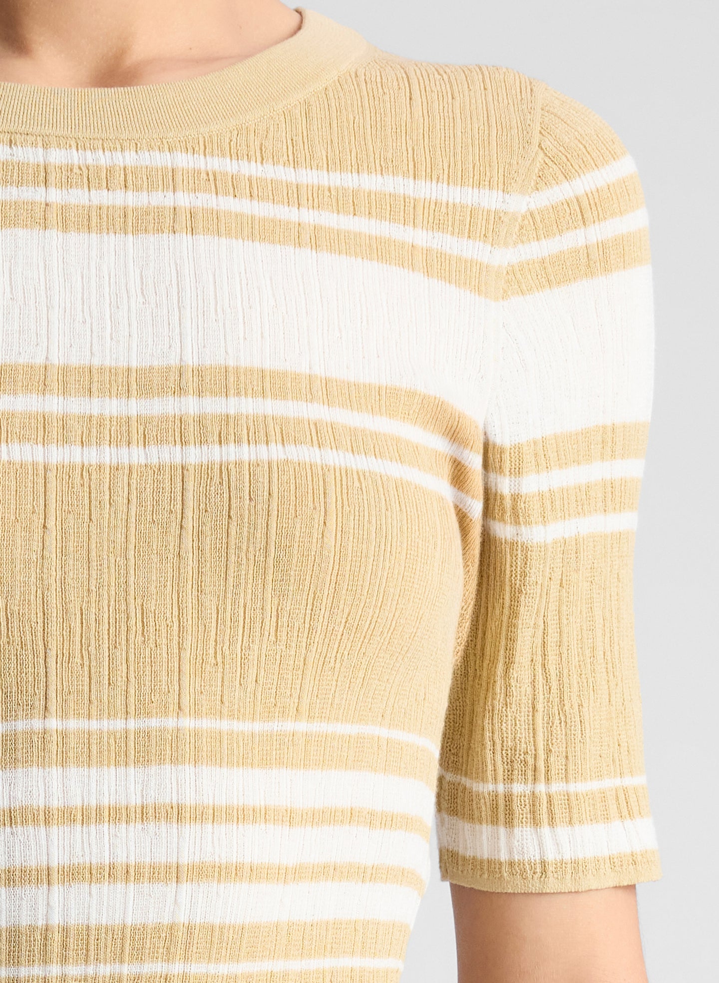 woman wearing tan and white striped top with white pants