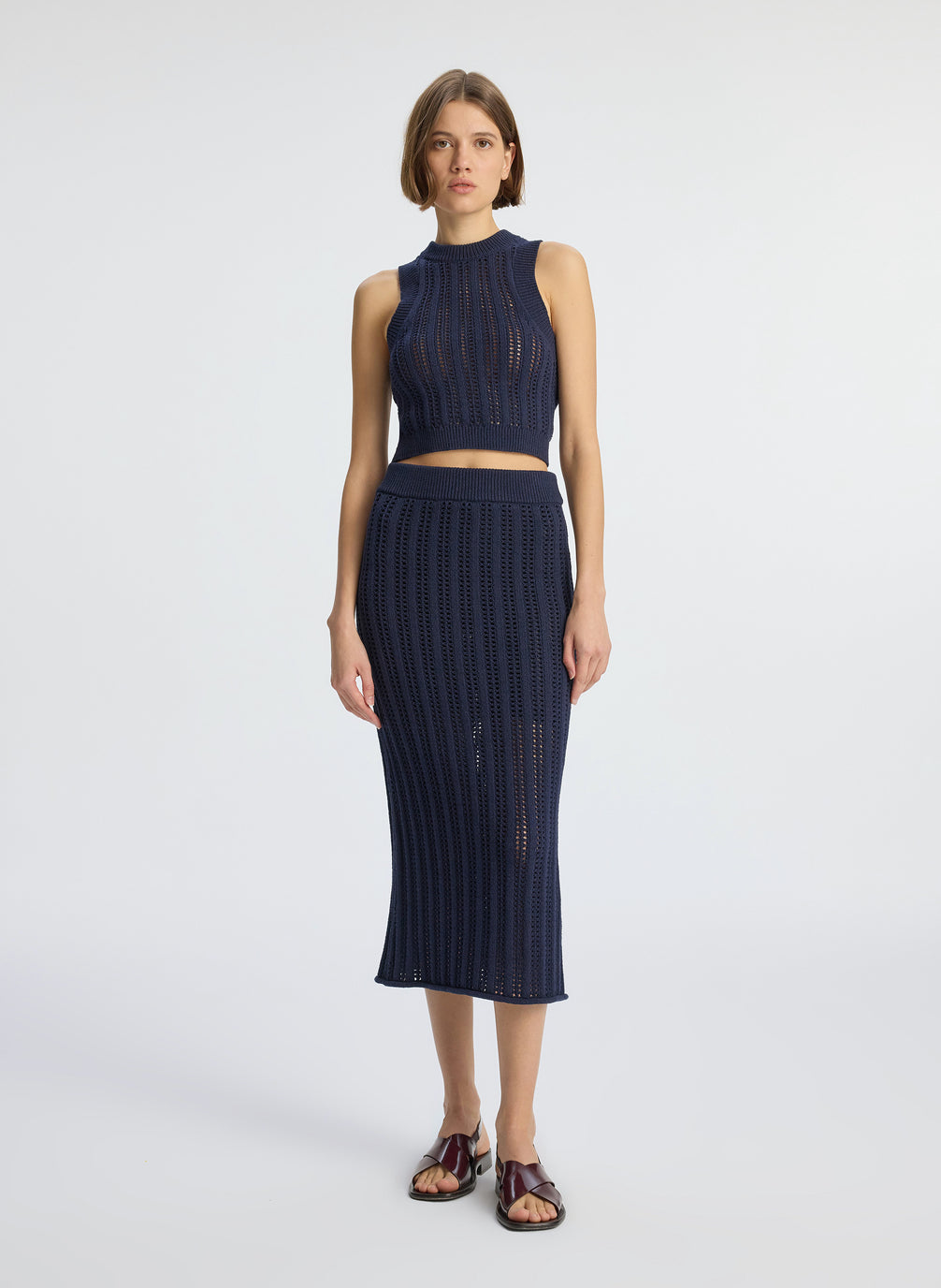front view of woman wearing navy blue open weave tank top and matching skirt