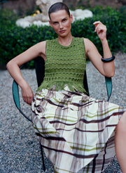 woman wearing green knit top and plaid midi skirt