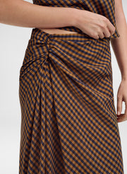 Close-up of a person wearing a brown and navy gingham wrap skirt with a gathered waist, paired with a matching gingham top.