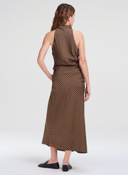 A woman shown from the back wearing a sleeveless top and matching skirt with a brown and beige geometric pattern, paired with black flats, against a light gray studio background.