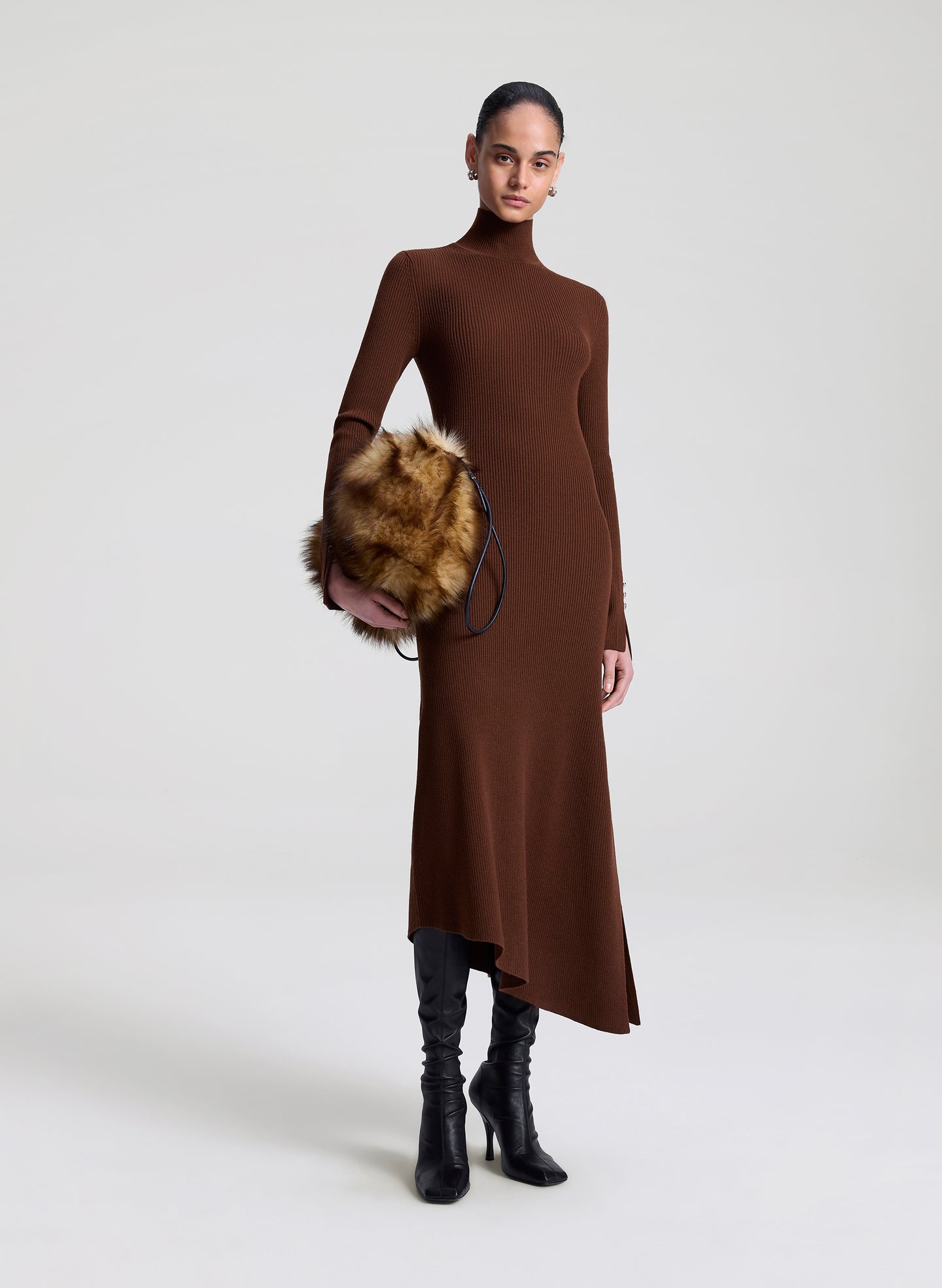 Woman wearing a brown dress holding a faux fur bag on a white background