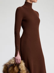 Woman wearing a brown dress holding a faux fur bag on a white background