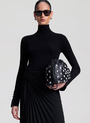 woman wearing black turtleneck and black pleated skirt