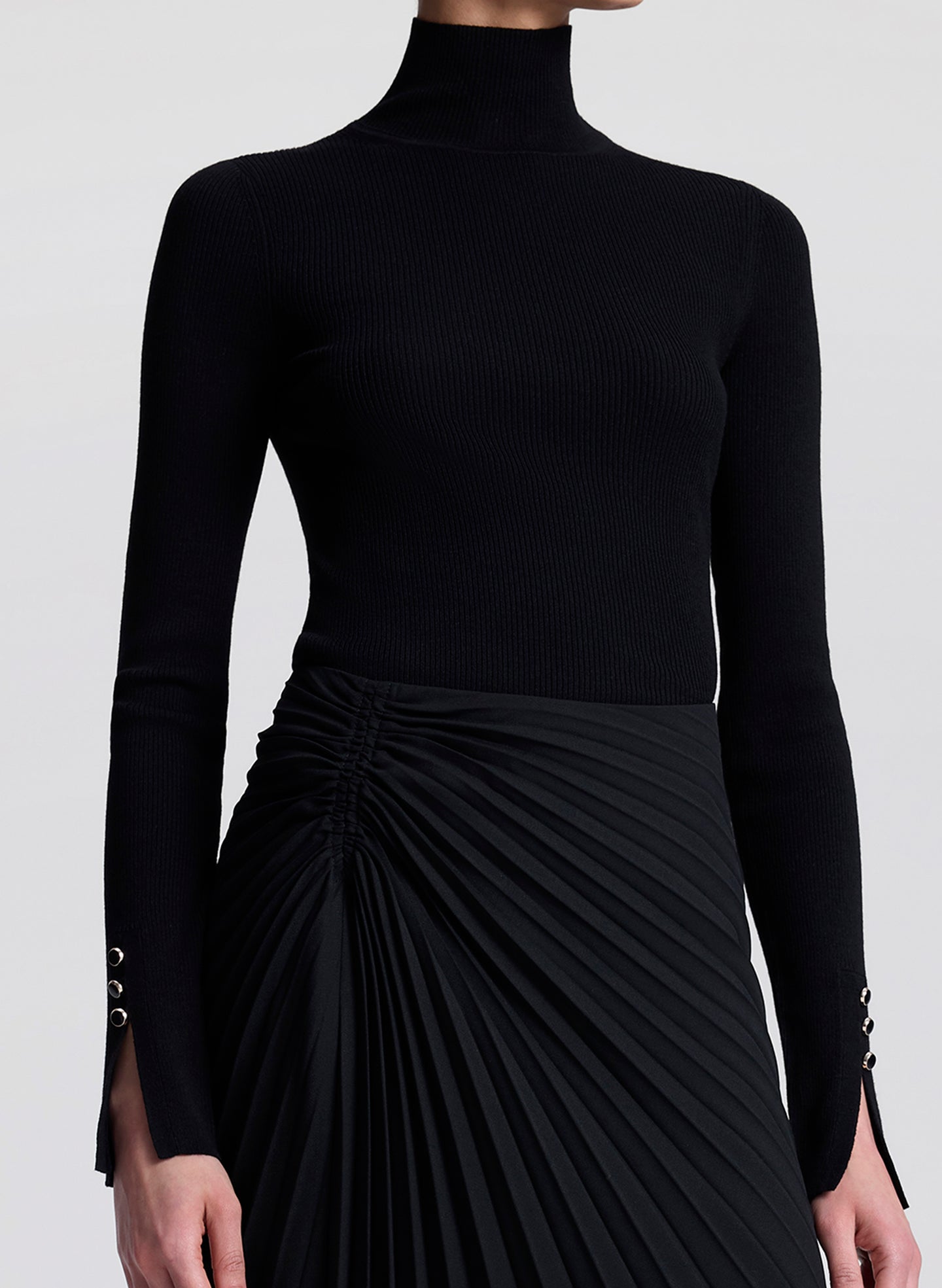 woman wearing black turtleneck and black pleated skirt